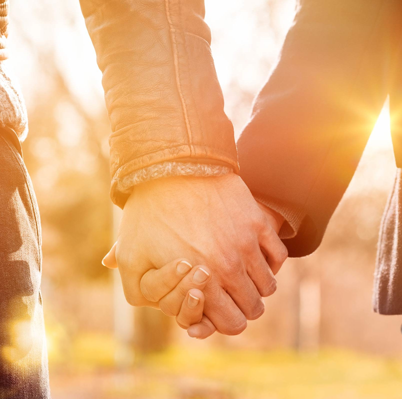 Zwei Hände, die sich vor Sonnenuntergang halten – Paartherapie und Paarberatung